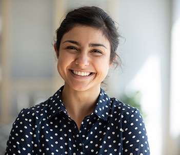 smiling person standing in front of a bookshelf