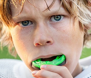 Teen boy placing green sports mouthguard
