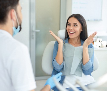 A woman pleased with her smile while talking to her dentist