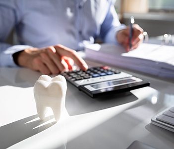 Fake tooth in front of a businessperson calculating a bill 