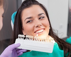 A young woman choosing the color of her teeth with a dentist