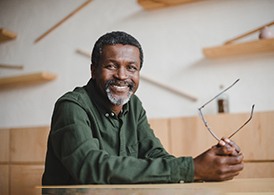 older man smiling while holding glasses