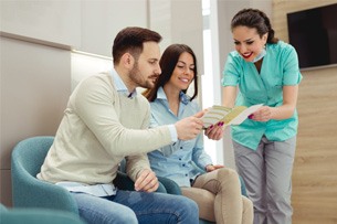 a front desk worker showing patients a brochure