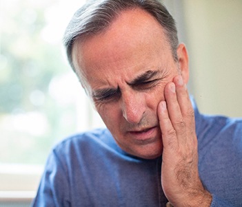 a person holding their mouth in pain because they have a toothache