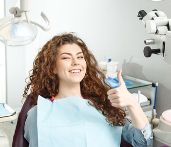 Woman smiling in dental chair with thumb up