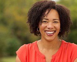 A middle-aged woman wearing an orange blouse smiles because of her renewed confidence