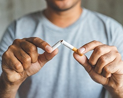 a person breaking a cigarette in half