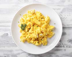 Scrambled eggs on a plate on wooden table