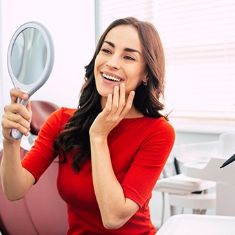 Woman admiring results of tooth recontouring in mirror