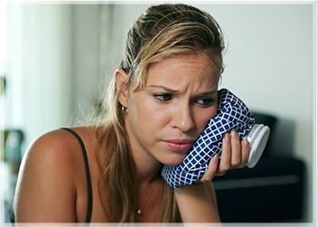 Woman holding icepack to cheek