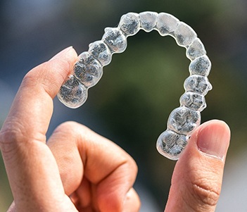 Close up of hand holding Invisalign clear aligners