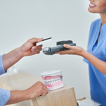 A man using a credit card to pay the cost of teeth whitening
