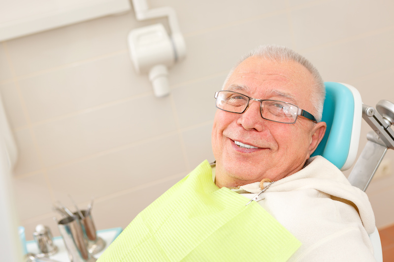 senior man smiling in dental chair