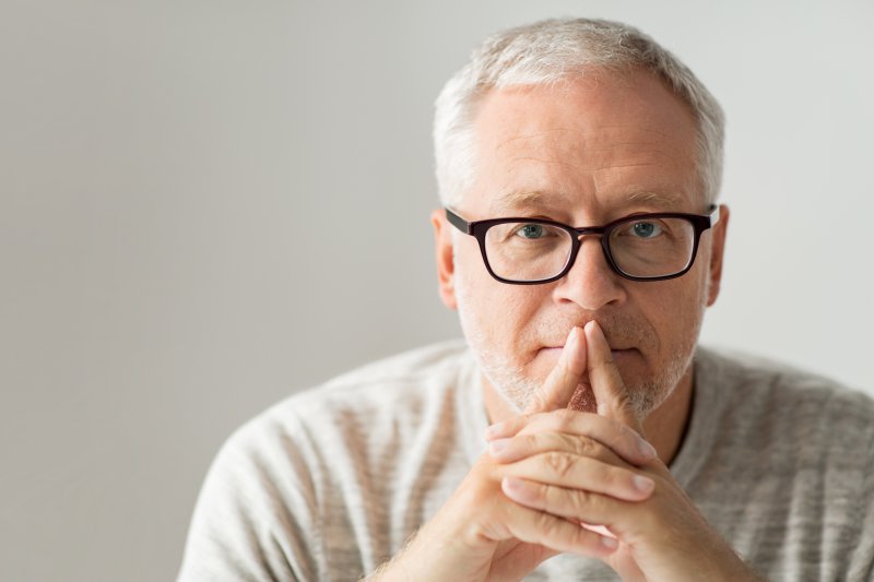 An older man covering his mouth.