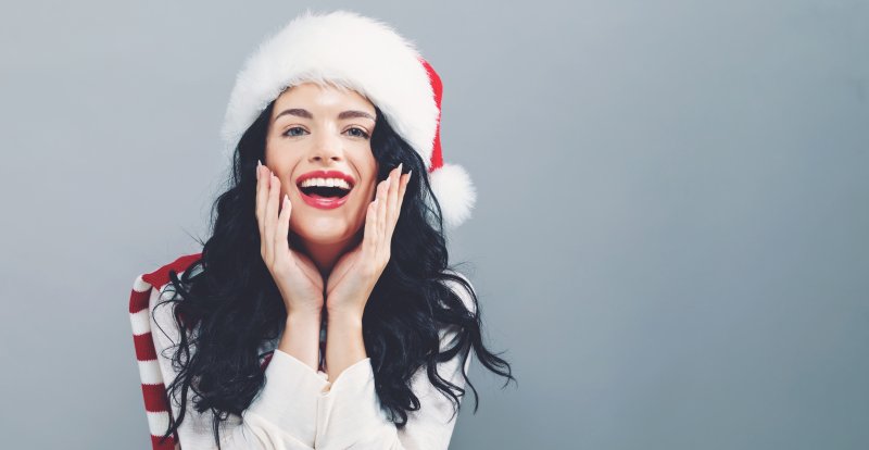 a young woman smiling while wearing a Santa hat