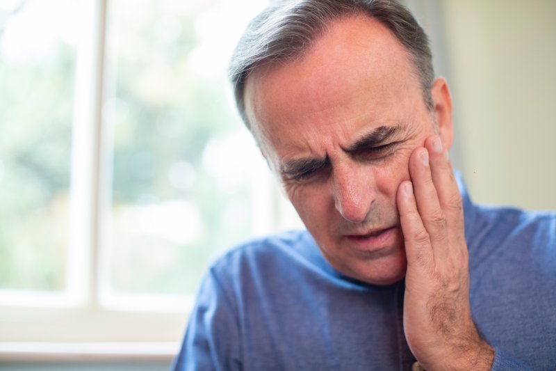 A man in pain debating on visiting an emergency dentist.