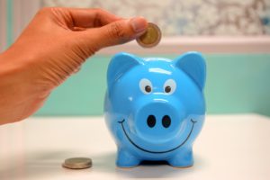 Hand putting coin in piggy bank