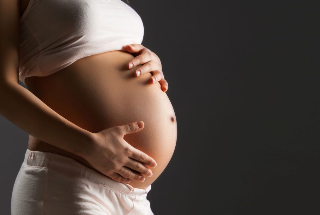 Closeup of pregnant belly with dark gray background