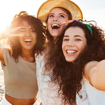 Selfie of three women at the beach smiling with veneers in Vero Beach