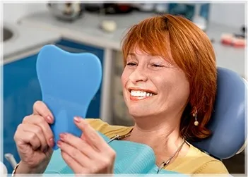 Smiling woman holding blue dental model showcasing enhanced smile and cosmetic dentistry.