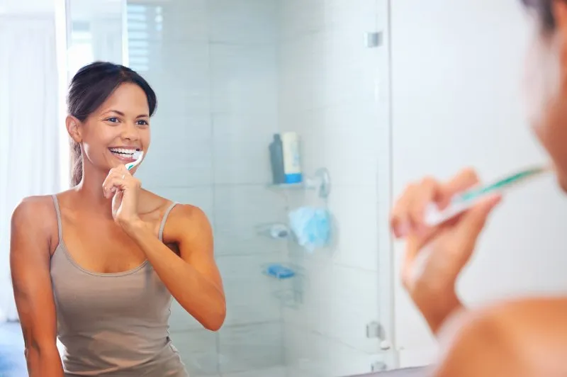 Woman smiling while brushing her teeth