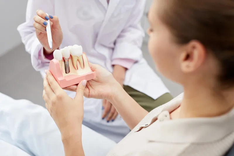 Patient looking at model as dentist explains dental implants