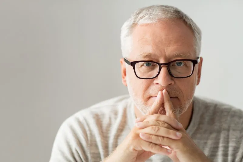 An older man covering his mouth.